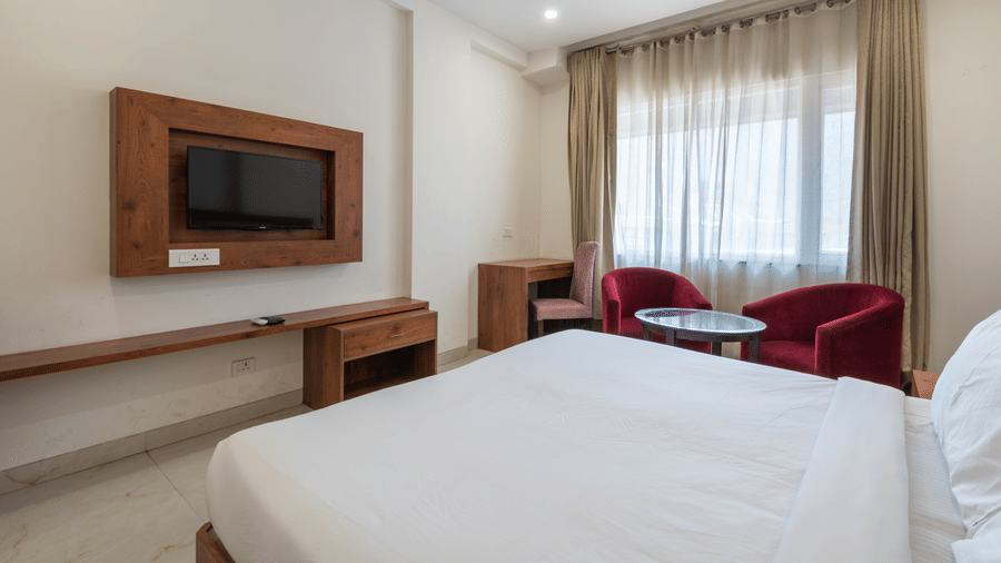 Club balcony room featuring a comfortable bed, wall-mounted TV, and a balcony partially covered by sheer curtains at DLS The Classio